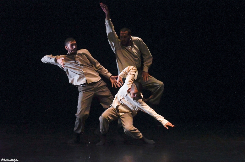 Three dancers on stage in mid-performance